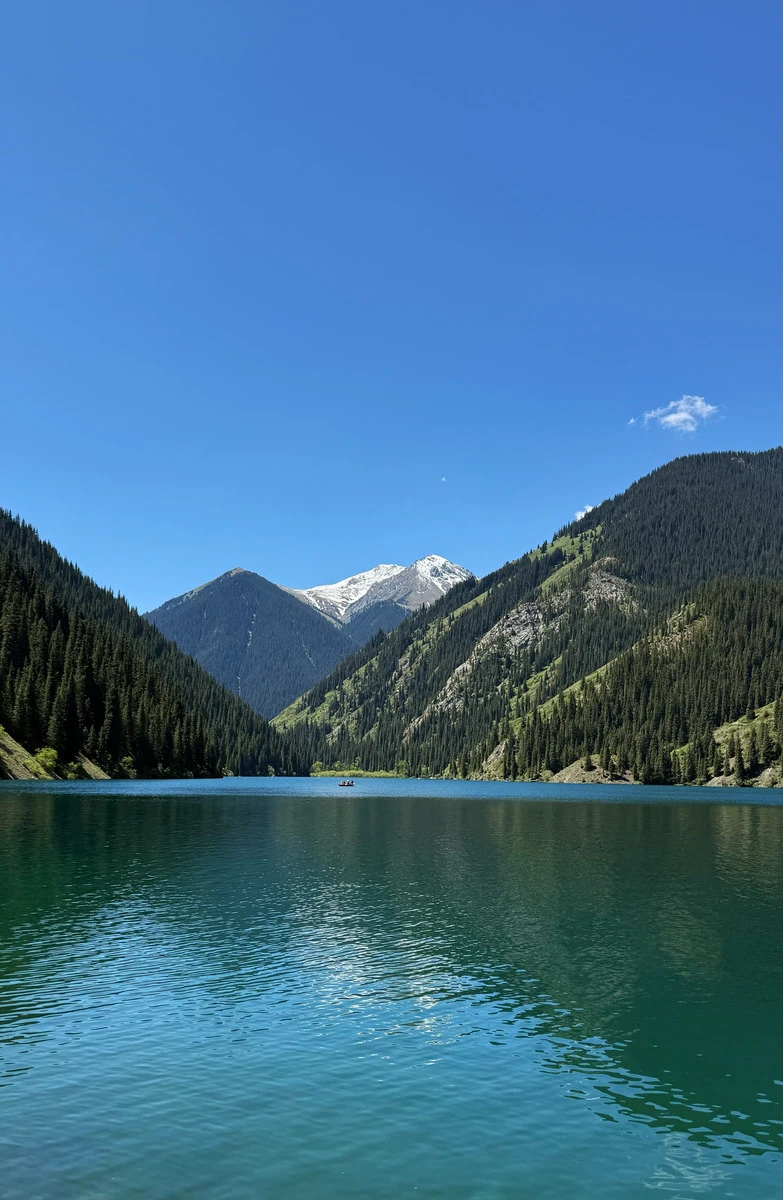 Aerial view of Kolsai Lake nestled between mountains in warm evening light